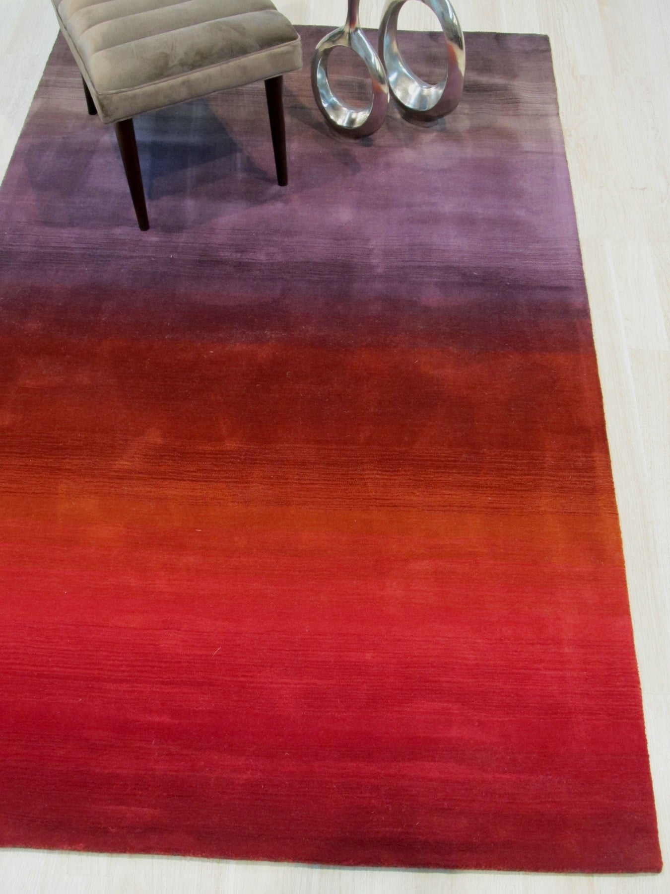 Rhea Unique Multicolor Handmade Wool Rug, sprawling across hardwood flooring, its vibrant hues of teal, gold, and coral interweaving in a captivating abstract pattern, a corner gently hinting at a nearby sofa.