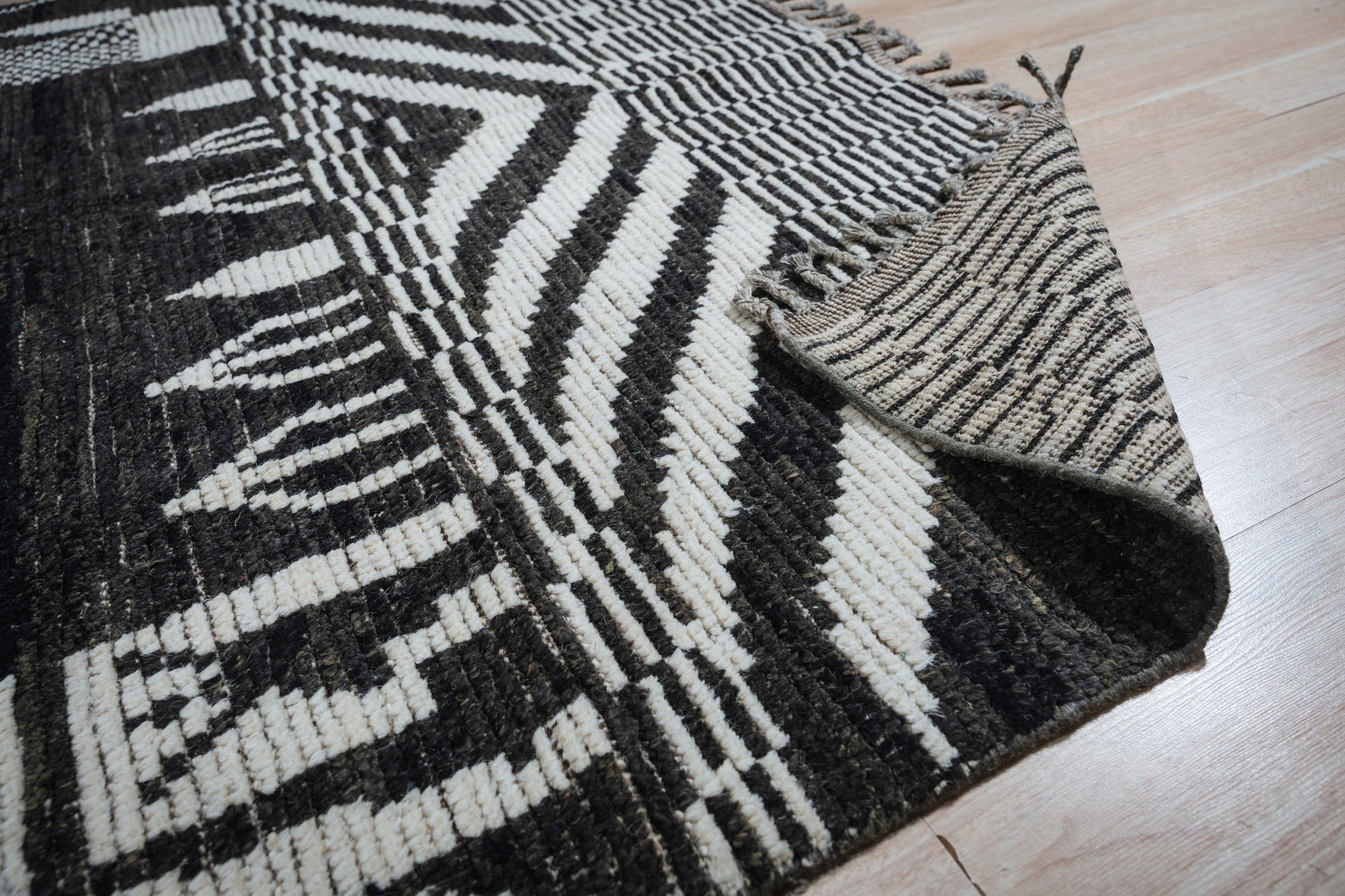 Marrakech Essence Black Rug, its intricate geometric pattern in contrasting tones adding a touch of Moroccan flair to a bright, modern living space.