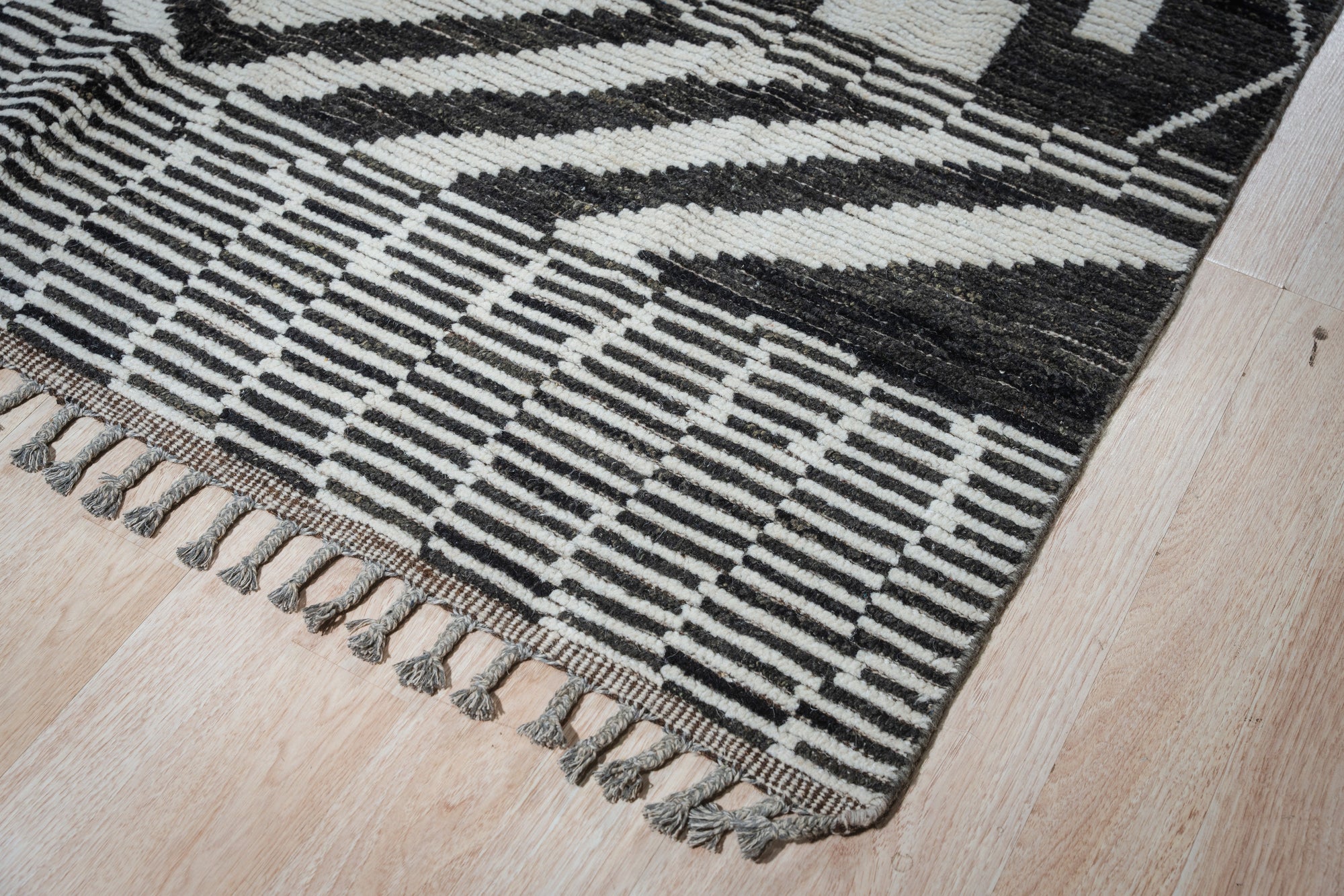 Marrakech Essence Black Rug layered in a warmly lit living space, its geometric pattern adding depth to the modern decor.