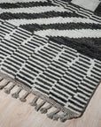Marrakech Essence Black Rug layered in a warmly lit living space, its geometric pattern adding depth to the modern decor.