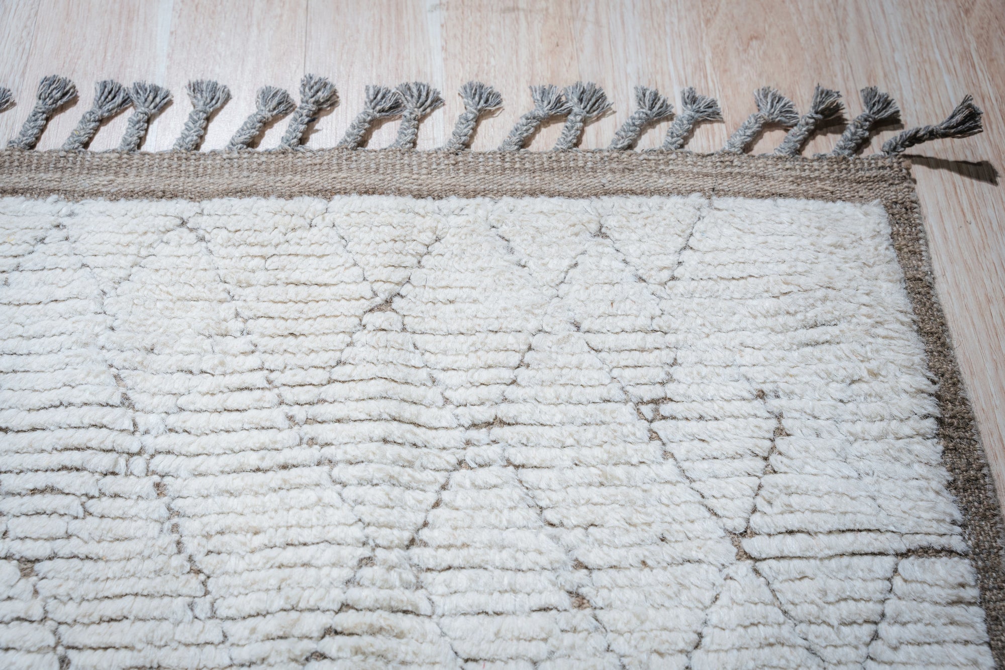 Marrakech Serenity Ivory Rug sprawls across a bright living space, its plush ivory texture inviting touch. Geometric patterns subtly etched into the rug add depth and a sense of sophisticated calm. A modern sofa and coffee table rest comfortably on its soft pile, suggesting a haven of relaxation and style.