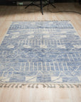 Elegant Marrakech Blue Hand-Knotted Wool Rug, showcasing its intricate geometric patterns and rich blue hues, rests on a light hardwood floor, creating a sophisticated living space.