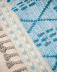 Stylish Marrakech Blue Hand-Knotted Wool Rug displayed in a modern living room, showcasing intricate geometric patterns and a vibrant blue hue complementing the neutral décor.