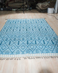 Stylish Marrakech Blue Hand-Knotted Wool Rug, vibrant blues and intricate geometric patterns unfold across this hand-knotted wool rug, showcased within a warmly lit interior space, inviting comfort and timeless style.