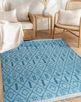 Stylish Marrakech Blue Hand-Knotted Wool Rug, showcasing an intricate geometric pattern in shades of blue and cream, laid out on a light hardwood floor, enhancing a living space.