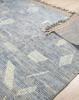 Charming Marrakech Blue Hand-Knotted Wool Rug, a vibrant blue wool rug with intricate geometric patterns, adding warmth and character to a well-lit room.