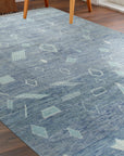 Charming Marrakech Blue Hand-Knotted Wool Rug, with intricate geometric patterns in varying shades of blue and cream, enriching a brightly lit living room setting.