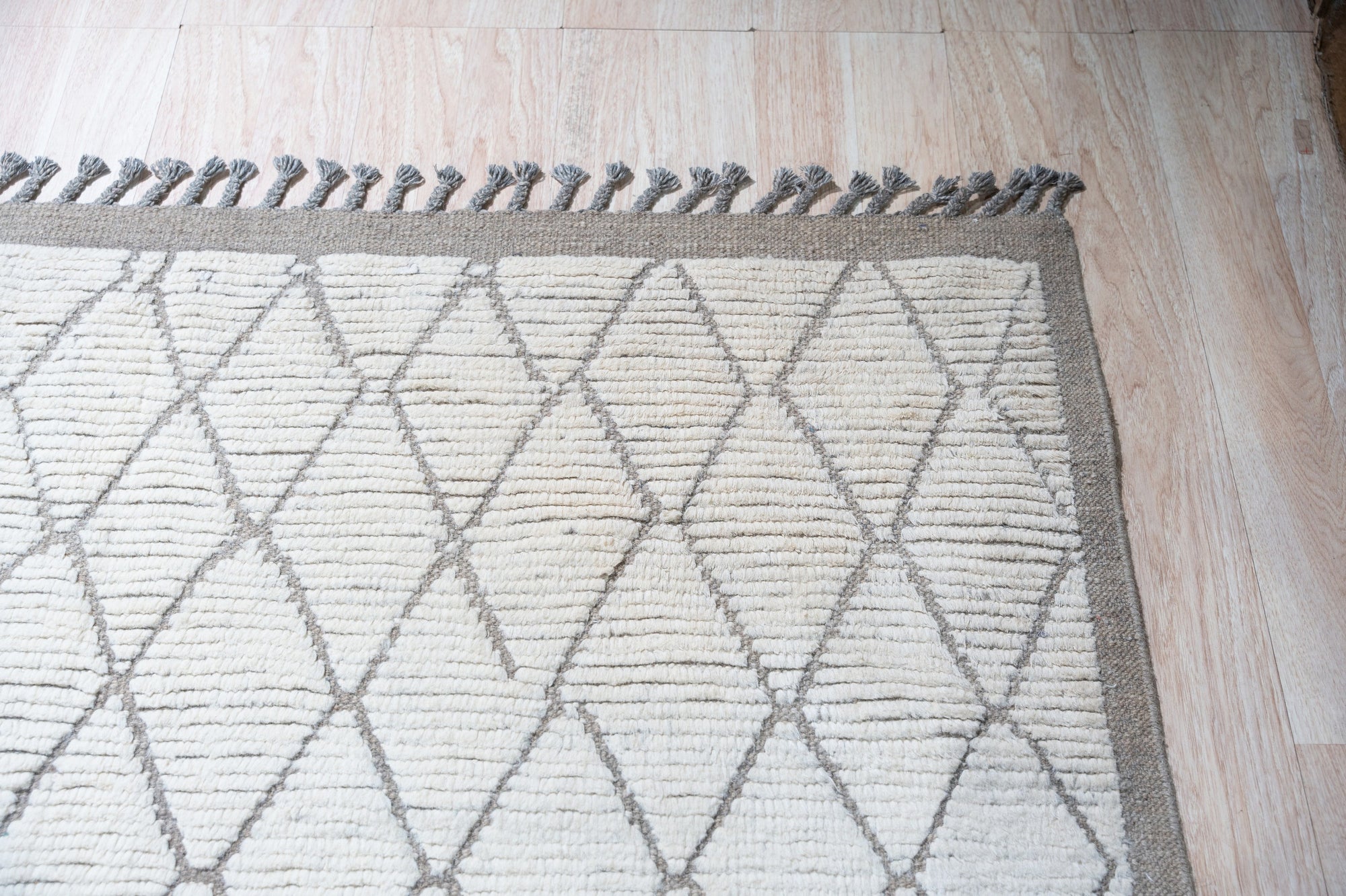 Refined Marrakech Beige Hand-Knotted Wool Rug, showcasing a geometric pattern in warm beige tones, subtly distressed for a vintage-inspired look, displayed in a well-lit living room setting.
