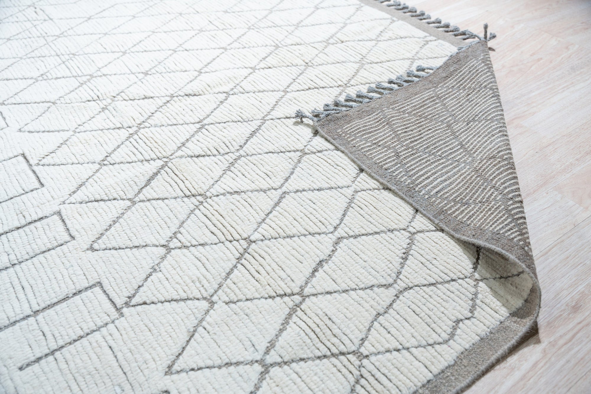 Refined Marrakech Beige Hand-Knotted Wool Rug, showcasing its intricate pattern and warm neutral tones, anchors a stylish living space with modern furniture and natural light.