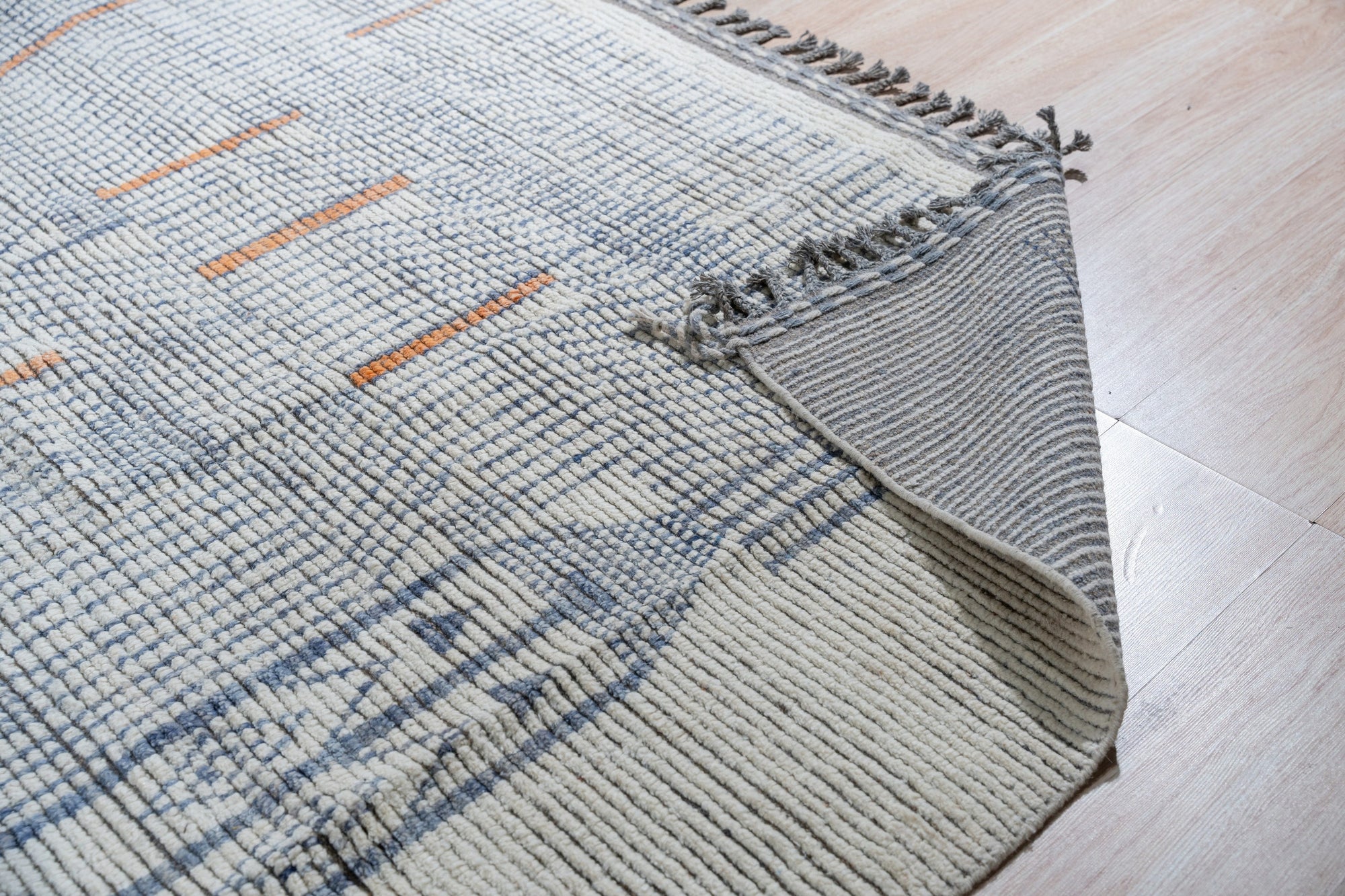 Subtle Marrakech Ivory Hand-Knotted Wool Rug, showcasing its intricate knotting and soft ivory hues, graces a warmly lit room, inviting touch and adding texture to the inviting space.