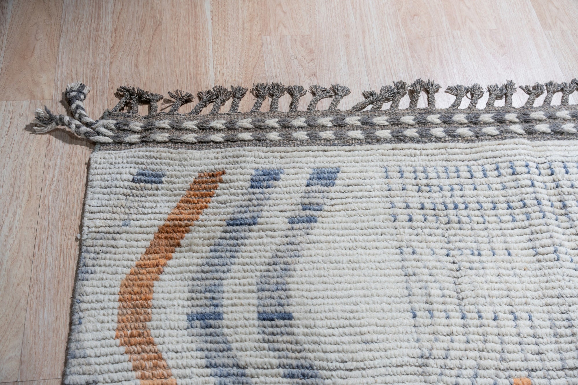 Abstract Marrakech Ivory Hand-Knotted Wool Rug, its subtle ivory tones and abstract design complementing a modern living space with neutral walls and light wood flooring, showcasing its hand-knotted construction.