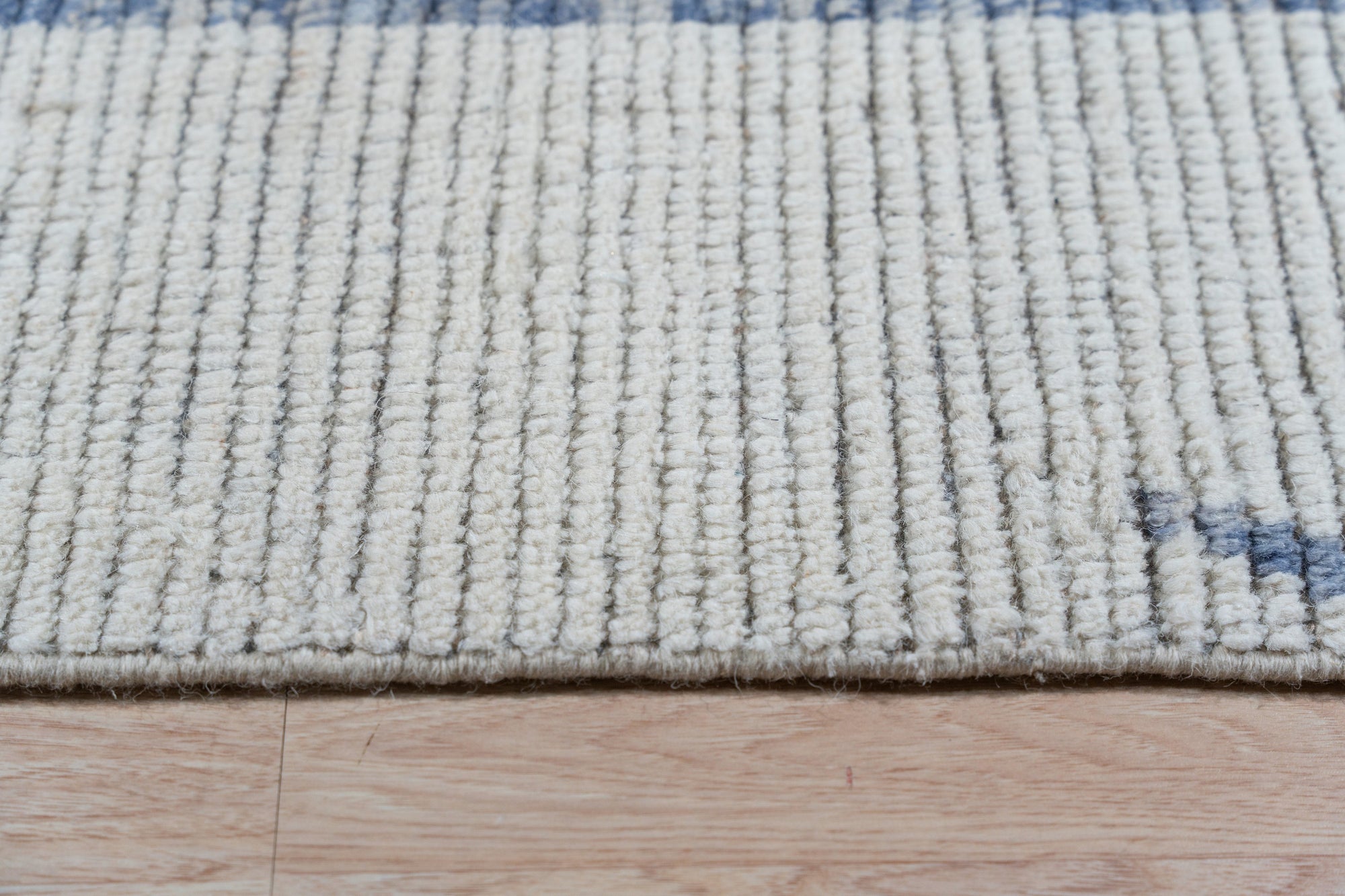 Abstract Marrakech Ivory Hand-Knotted Wool Rug, showcasing its texture and subtle patterns in a brightly lit room.