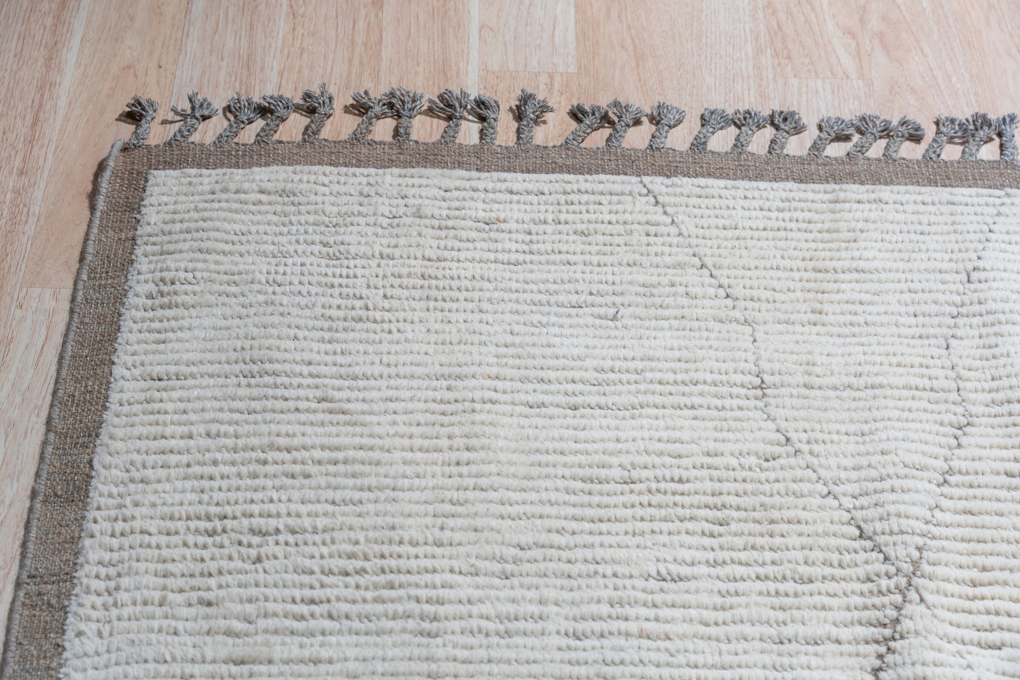 Sophisticated Marrakech Brown Hand-Knotted Wool Rug, its warm brown tones and intricate geometric pattern grounding a modern living room with a plush sofa and natural light.