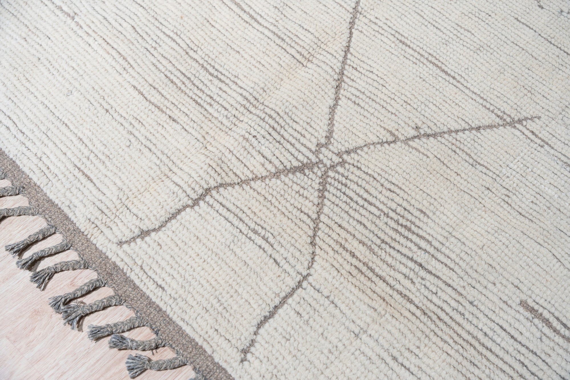 Sophisticated Marrakech Brown Hand-Knotted Wool Rug, showcasing intricate geometric patterns in warm browns and creams, laid on a polished wood floor, its texture inviting and luxurious.