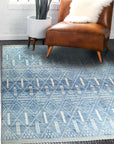 Refined Marrakech Blue Hand-Knotted Wool Rug, its intricate geometric patterns in shades of blue and cream lending an air of sophisticated comfort to a brightly lit living space.