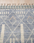 Timeless Marrakech Blue Hand-Knotted Wool Rug, a blue and wool rug with a geometric design, seen in a styled living room setting.