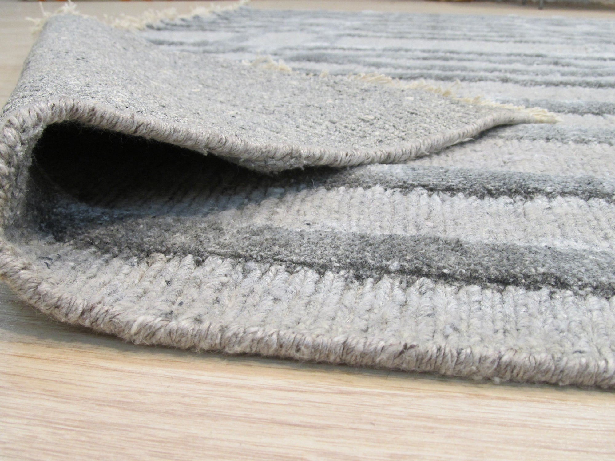 Para Talia Gray Hand Knotted Wool & Viscose Rug, showcasing a subtly textured, soft gray field with a delicate sheen. The rug adds understated elegance to a bright, minimalist living space.