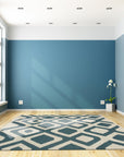Opulent Kilim Blue Hand Knotted Rug, exhibiting intricate geometric patterns in shades of blue and ivory, displayed within a brightly lit interior.
