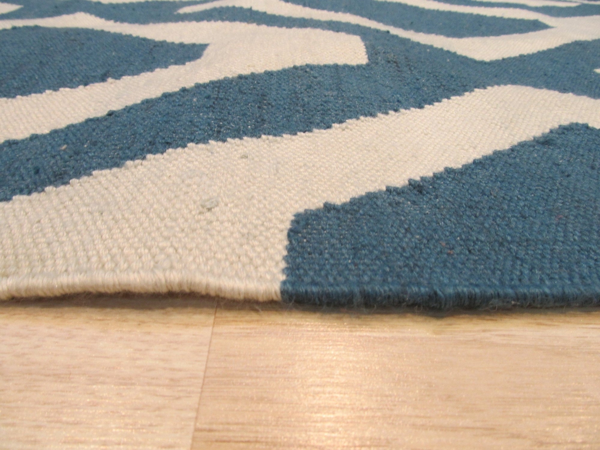 Opulent Kilim Blue Hand Knotted Rug, its intricate geometric patterns in shades of blue, ivory, and hints of rust, adding warmth and sophistication to a subtly textured setting.