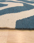 Opulent Kilim Blue Hand Knotted Rug, its intricate geometric patterns in shades of blue, ivory, and hints of rust, adding warmth and sophistication to a subtly textured setting.