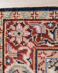 Ella Oriental Navy Hand Knotted Wool Rug, its intricate navy and ivory pattern sprawling across the hand-knotted wool pile, softening a warmly lit interior.