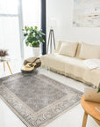Rhea Elena Purple Hand Knotted Wool Rug, displaying intricate patterns in shades of purple, cream, and gray, subtly lit to showcase its hand-knotted texture.