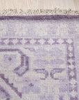 Rhea Elena Purple Hand Knotted Wool Rug, blending shades of violet and lavender in a nuanced, hand-knotted wool texture, graces a neutral-toned interior, its intricate pattern adding warmth and sophisticated elegance.