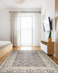 Rhea Elena Purple Hand Knotted Wool Rug, displaying a swirling, abstract design with shades of deep purple and subtle variations, lending a sophisticated and artistic flair to a warmly lit room setting.