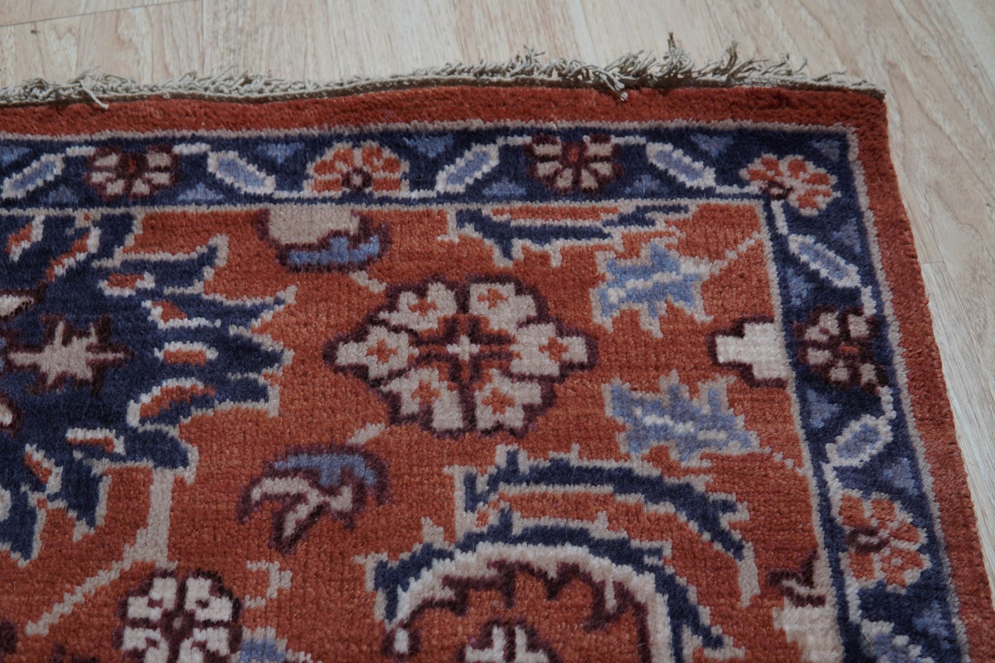 Lush Rustic Rust Hand Knotted Wool Rug, a blend of earthy rust tones in hand-knotted wool, adding warmth and texture to a living space with hardwood flooring.