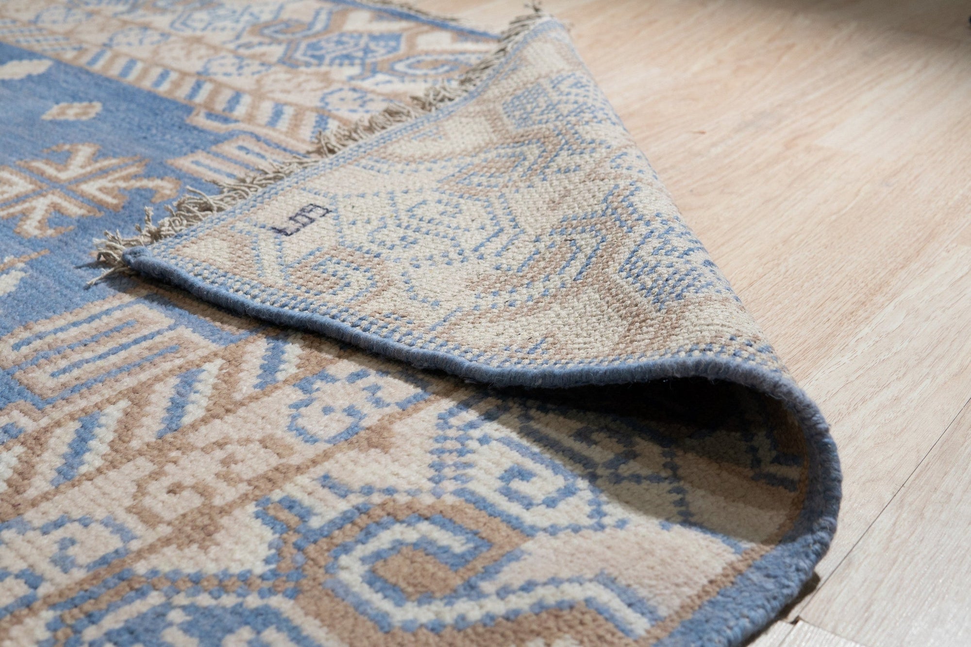 Handcrafted Traditional Blue Hand Knotted Wool Rug, showcases intricate patterns and rich blues against a warm background, lying flat and ready to add timeless elegance to any space.