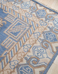 Handcrafted Traditional Blue Hand Knotted Wool Rug, richly patterned with classic motifs in deep blues and subtle creams, lies elegantly on a polished floor, hinting at warmth and timeless style within a softly lit room.