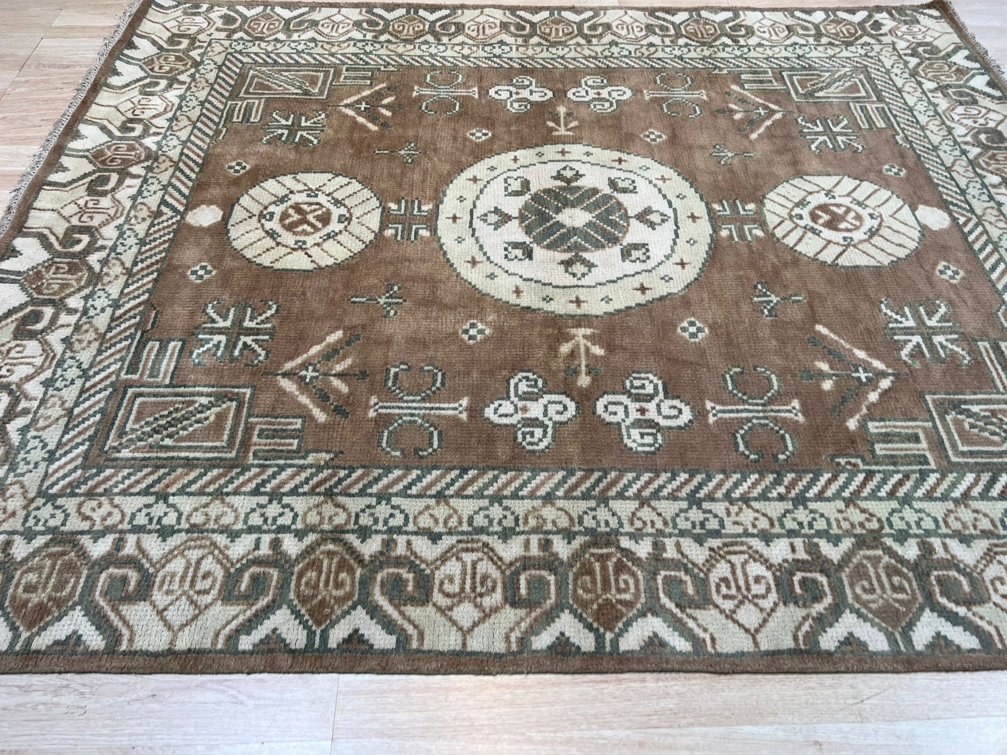 Trendy Traditional Brown Hand Knotted Wool Rug, a brown wool rug with a traditional design, seen in a bright, neutral room setting showcasing its pattern and texture.