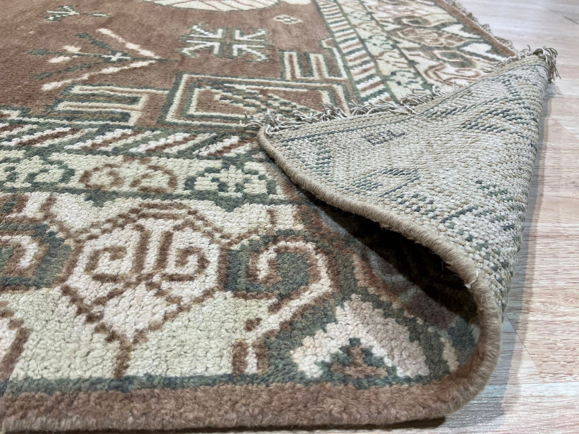 Trendy Traditional Brown Hand Knotted Wool Rug, showcasing a complex, traditional pattern in warm browns and creams. The hand-knotted construction is visible, suggesting high quality and durability. Seen in a styled setting, hinting at its ability to complement various decors.