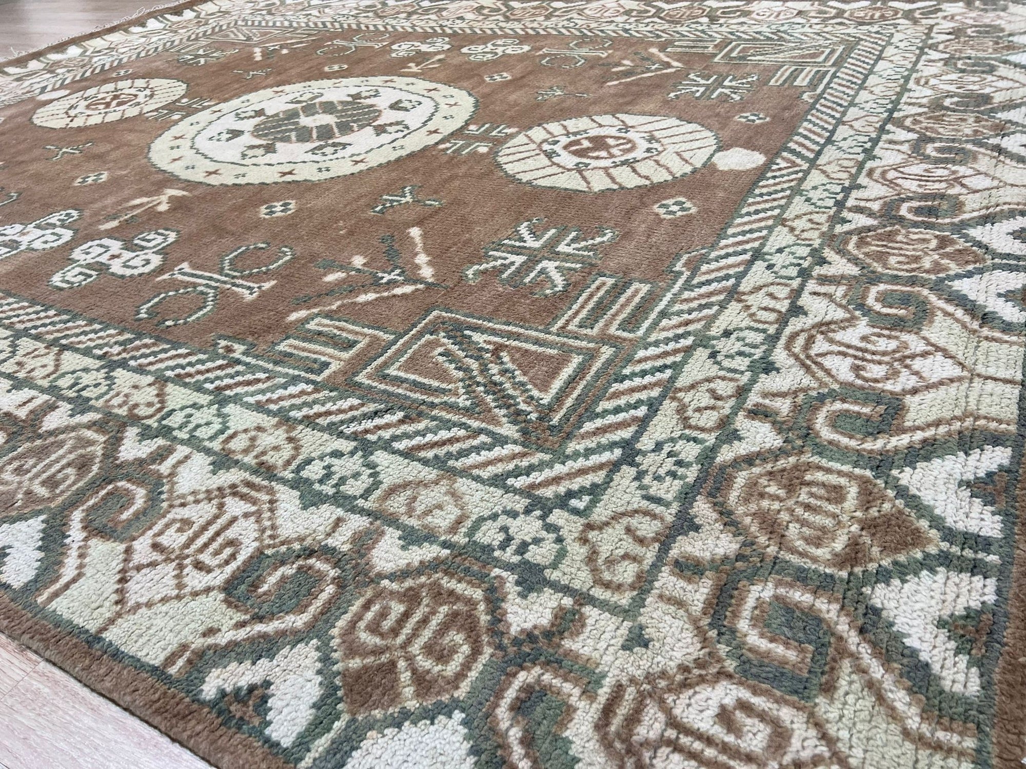 Trendy Traditional Brown Hand Knotted Wool Rug, showcasing warm brown tones and intricate traditional patterns, displayed in a brightly lit room with modern furniture.