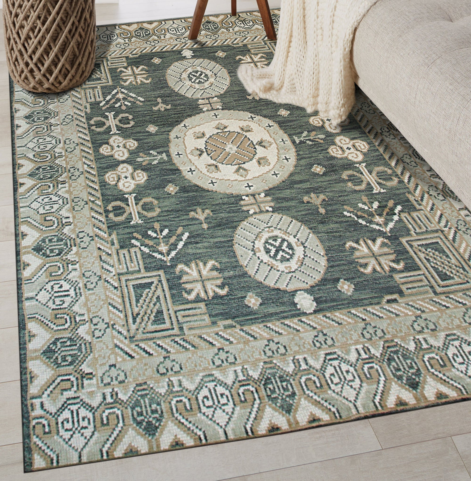 Rhea Traditional Green Hand Knotted Wool Rug, displaying intricate floral patterns in shades of green, cream, and hints of red, gracing a light hardwood floor under soft, diffused light.