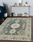 Rhea Traditional Green Hand Knotted Wool Rug, a lush green wool rug with an intricate traditional design, complementing a warmly lit living room setting with dark wood furniture and a patterned armchair.