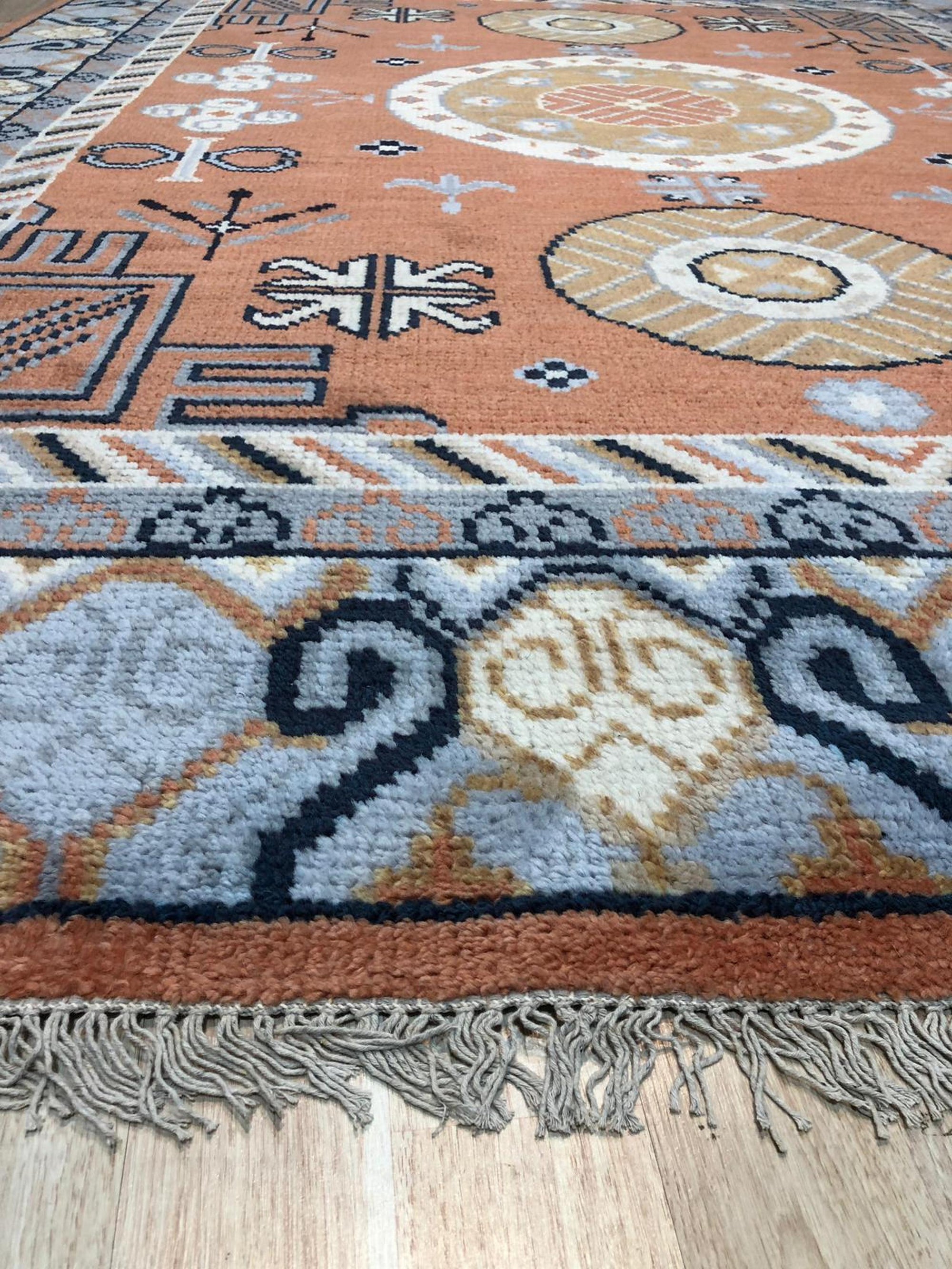 Jade Traditional Rust Hand Knotted Wool Rug displayed with warm, inviting lighting. Hand-knotted wool construction evident in the intricate pattern featuring rust hues and traditional motifs.