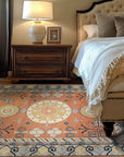 Jade Traditional Rust Hand Knotted Wool Rug, richly patterned in deep rust and jade, rests on a polished wood floor. Warm, inviting tones and intricate traditional design details fill a well-lit interior.