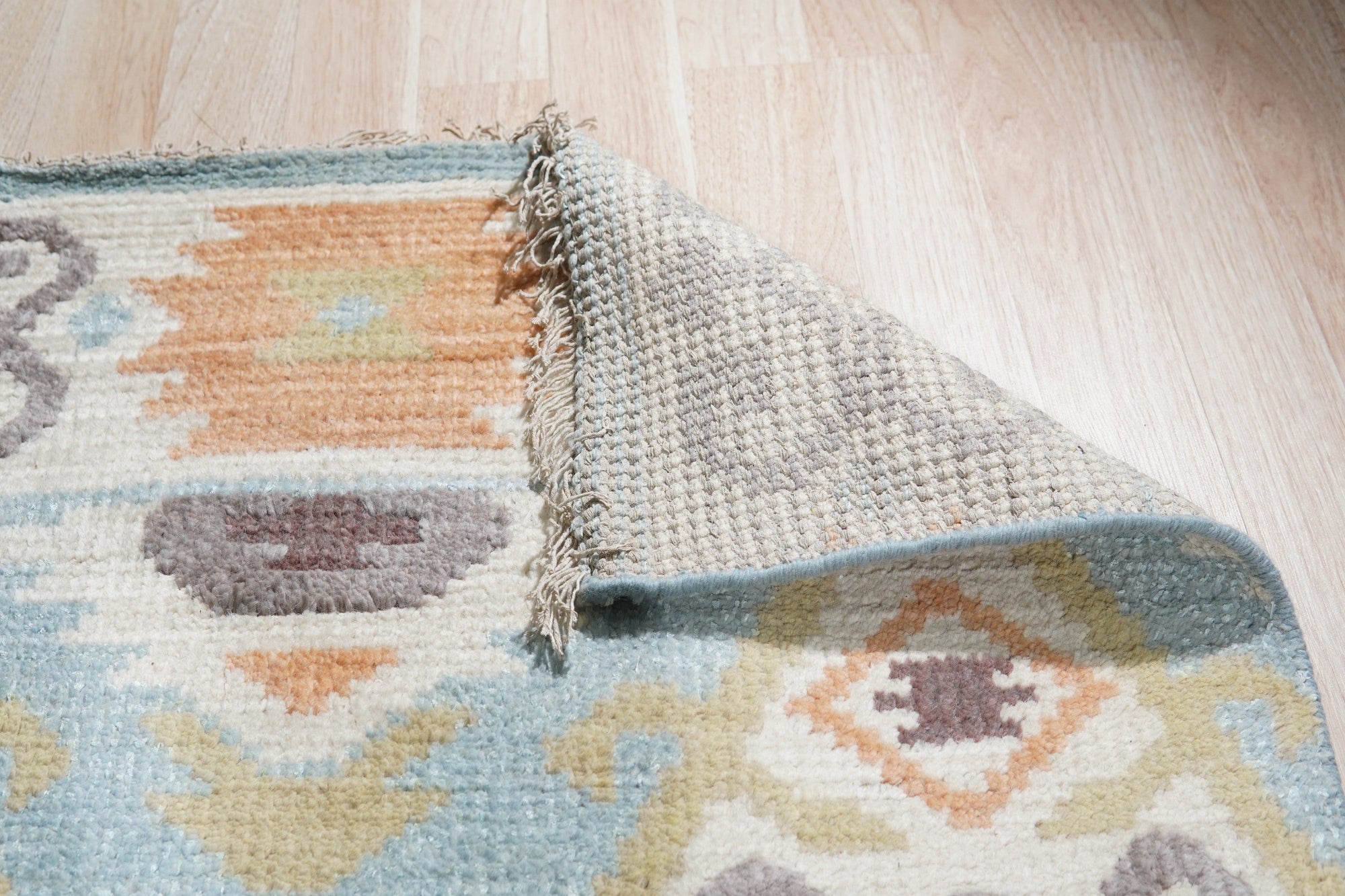 Freya Traditional Blue Hand Knotted Wool Rug, showcasing intricate floral patterns and ornate borders in shades of blue and cream, lays elegantly in a bright living room setting.