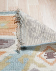 Freya Traditional Blue Hand Knotted Wool Rug, showcasing intricate floral patterns and ornate borders in shades of blue and cream, lays elegantly in a bright living room setting.