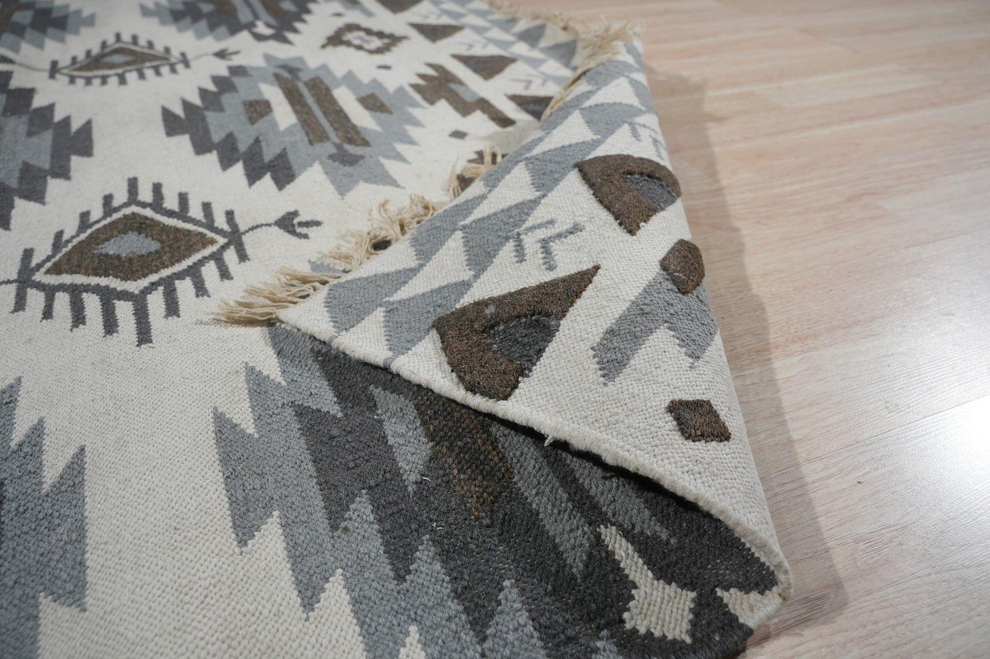 Chic Kilim Ivory Flatweave Rug, showcasing a geometric design in muted ivory tones with subtle variations, adds texture and warmth to a brightly lit living space.
