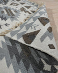 Chic Kilim Ivory Flatweave Rug, showcasing a geometric design in muted ivory tones with subtle variations, adds texture and warmth to a brightly lit living space.