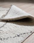 Jade Trellis Beige Hand Knotted Wool Rug, its intricate trellis pattern in beige wool subtly textured against a neutral backdrop, enriching a warmly lit room setting.