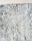 Captivating Moroccan Gray Hand Knotted Wool Rug, its geometric diamond pattern visible in soft grays and creams against a neutral background, enriching a styled living space.