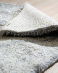 Captivating Moroccan Gray Hand Knotted Wool Rug, showcased in a styled living room setting, features a subtle geometric pattern in shades of gray and off-white, bringing warmth and texture to the modern space.