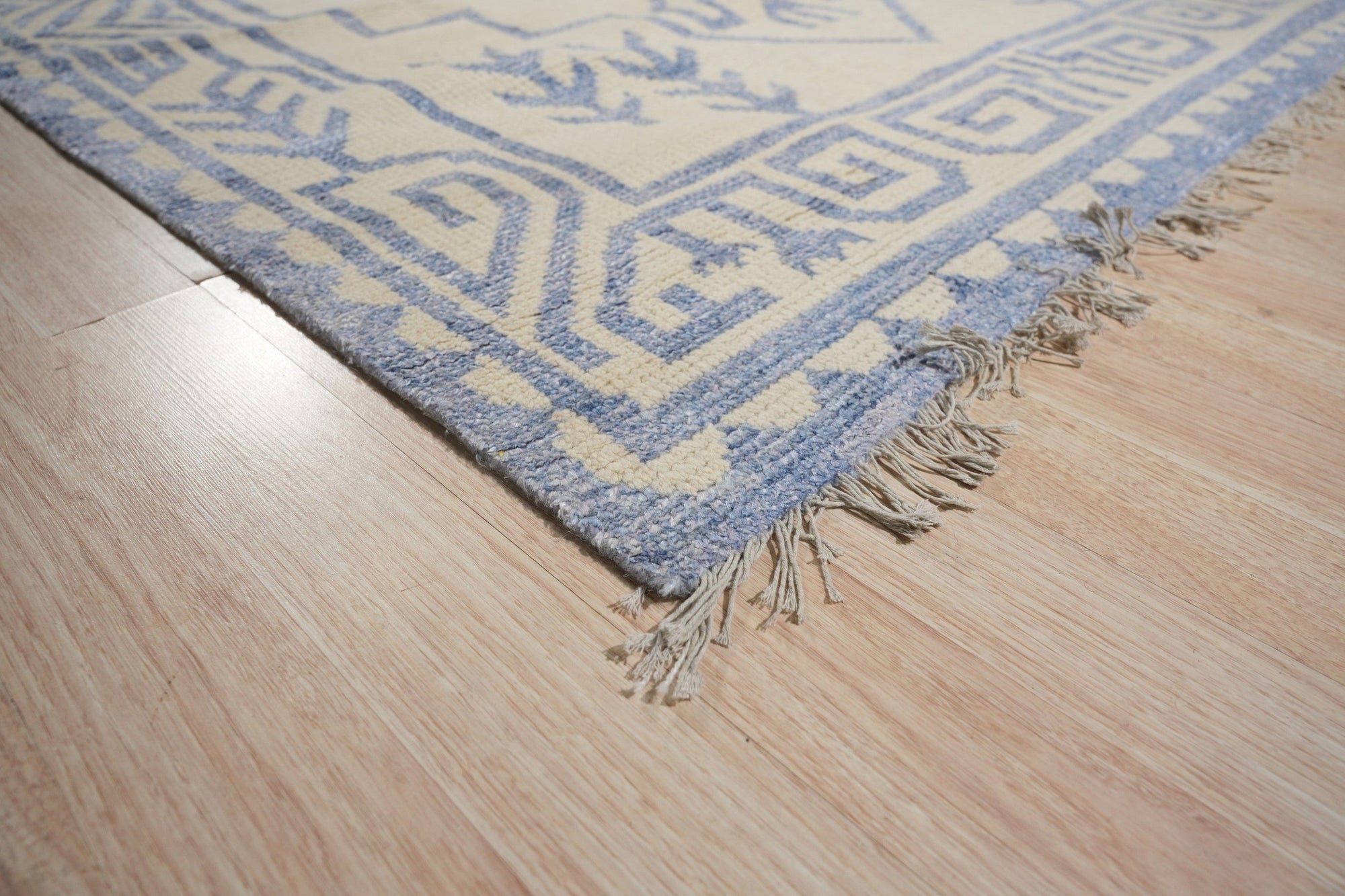 Louie Trara Blue Hand Knotted Wool & Bamboo Silk Rug, its intricate design unfolding in shades of blue and subtle sheen of silk threads, filling a warmly lit living space.