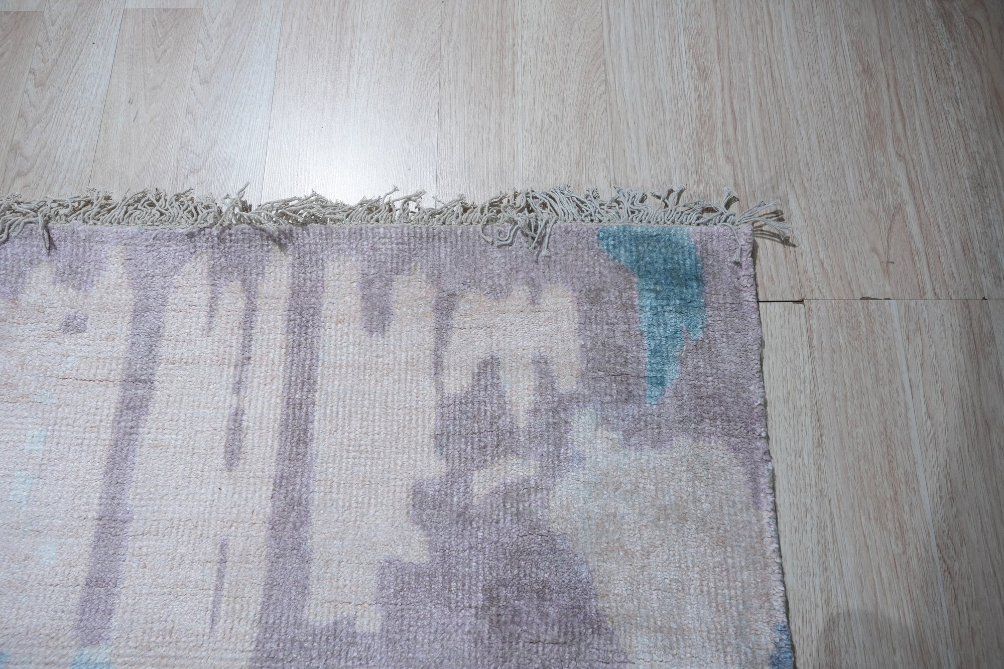Iris Bianca Multicolor Hand Knotted Bamboo Silk Rug, a vibrant splash of color and luxurious texture, lies elegantly on a light hardwood floor, its intricate design and shimmering bamboo silk fibers catching the light.
