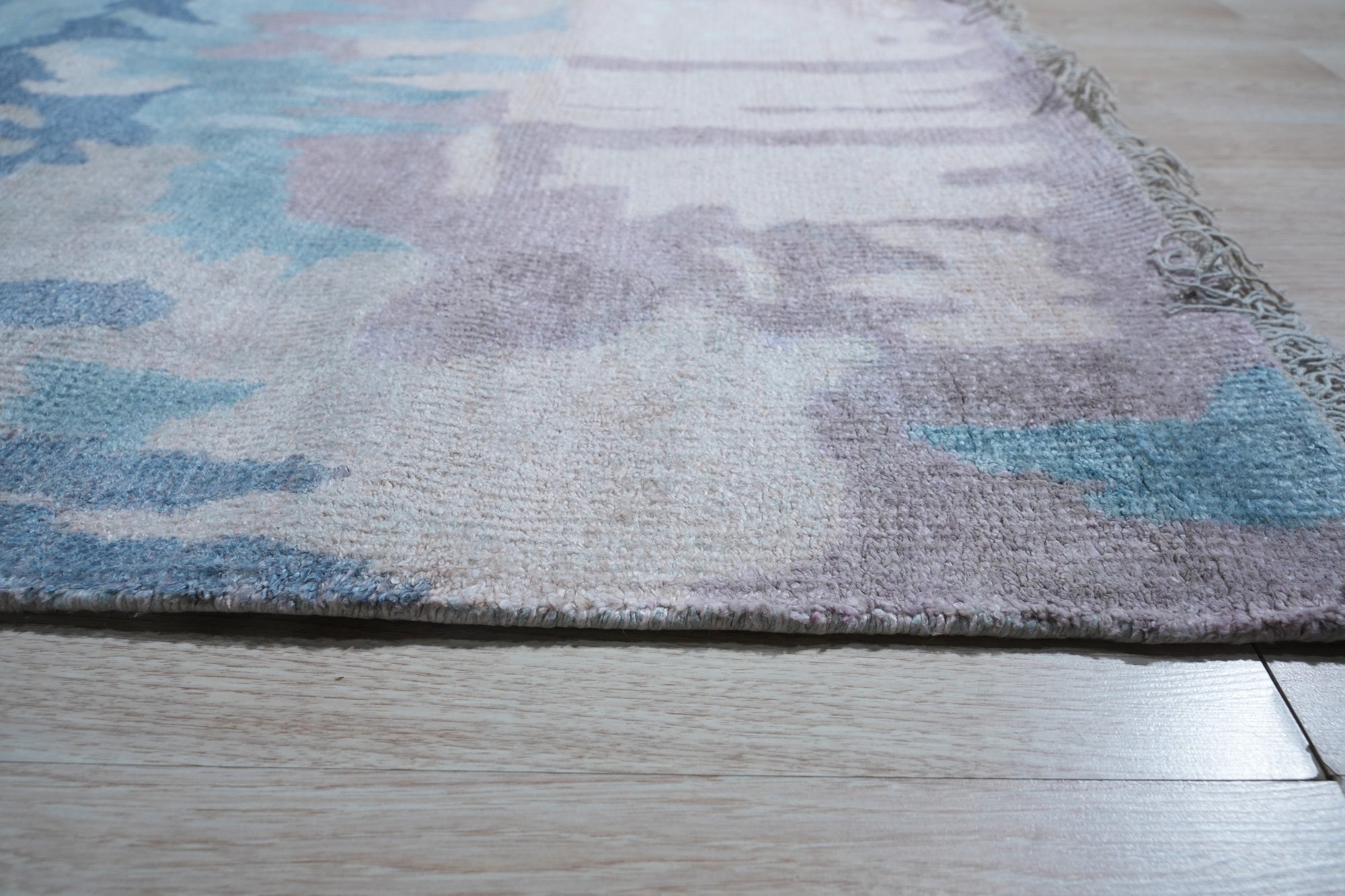 Iris Bianca Multicolor Hand Knotted Bamboo Silk Rug, showcasing vibrant hues and intricate knotwork, softens a contemporary living space with its luxurious sheen.