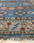 Charming Refined Blue Hand Knotted Wool Rug, its intricate pattern a blend of traditional and modern aesthetics, lies on a polished hardwood floor, casting subtle shadows that highlight its luxurious texture.