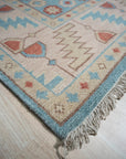 Yara Willow Light Blue Hand Knotted Wool Rug, displayed in a bright, contemporary living space. Light blue tones and subtle willow pattern enhance a cream sofa and warm wood flooring.